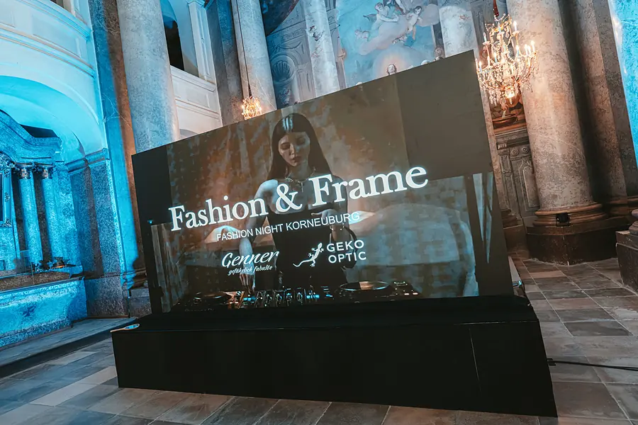 LED-Wand mit Fashion-&-Frame-Logo auf der Bühne im blau beleuchteten Saal